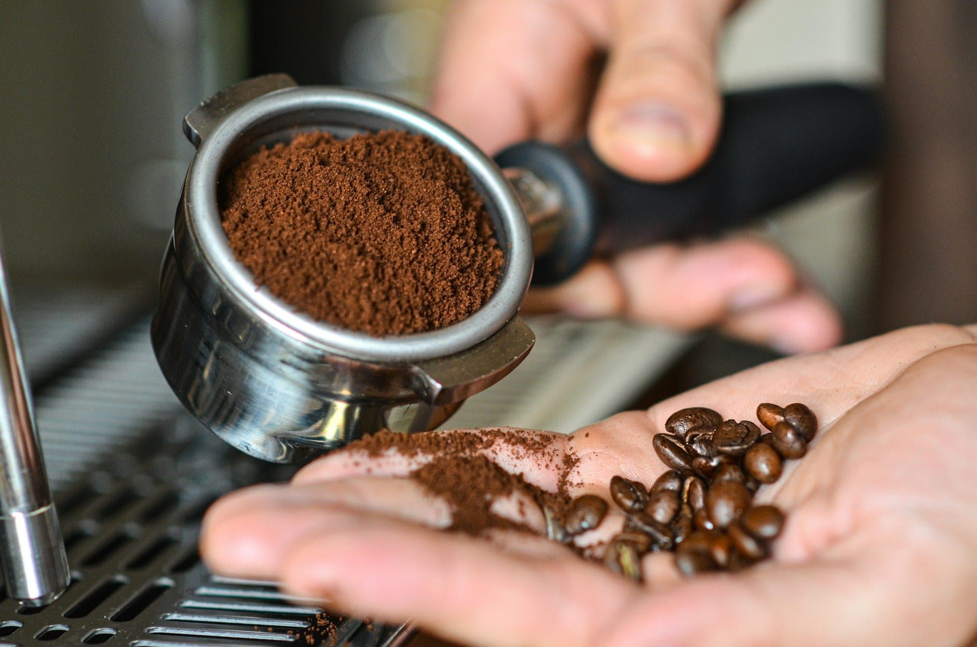 Sveže samlevena kafa u portafilteru i zrna na dlanu